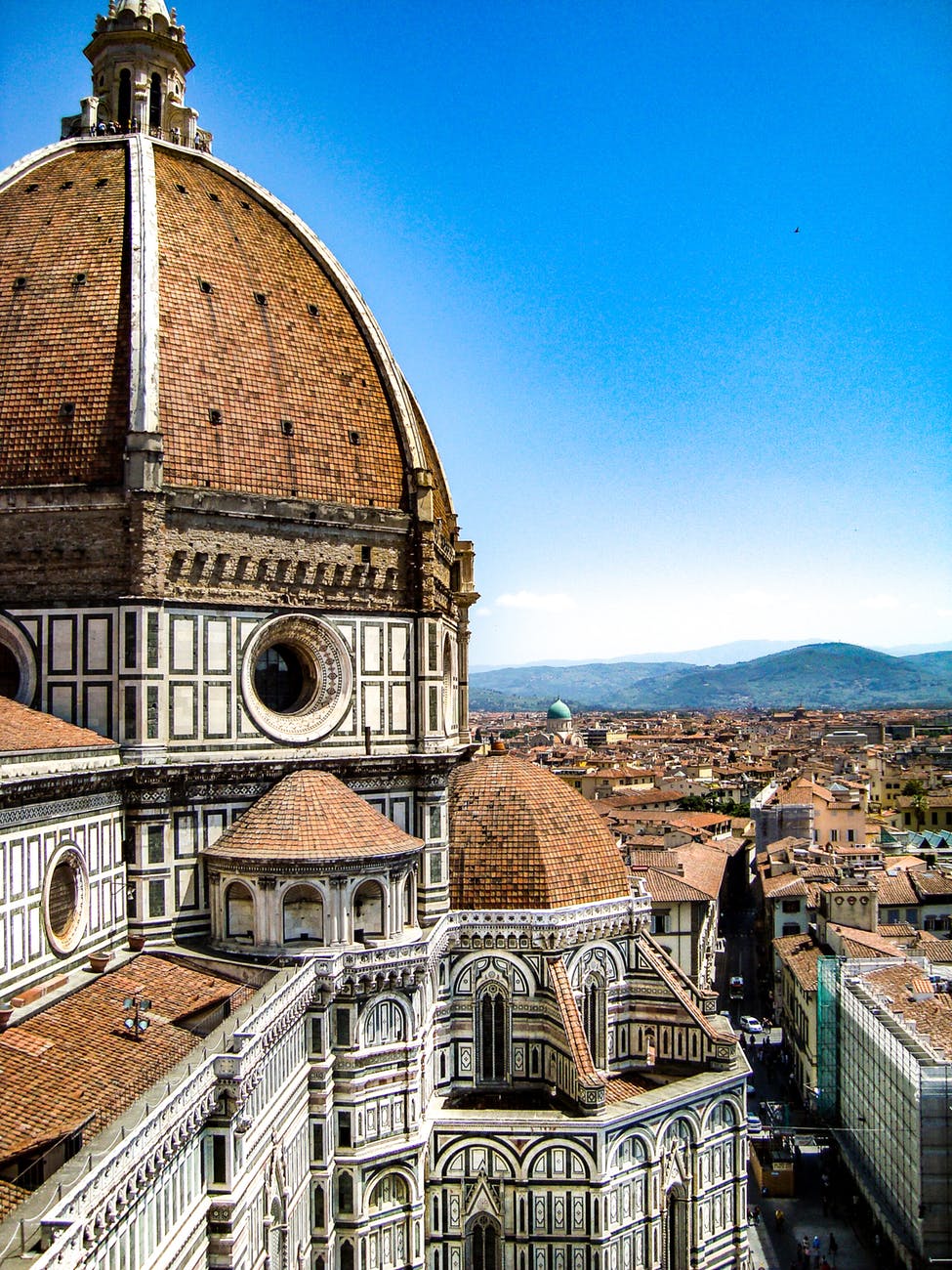brown and white painted cathedral roof overlooking city and mountain under blue sky
